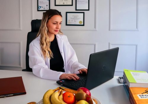 Dietitian at desk with fruits and laptop, representing healthy lifestyle and nutrition consultancy.